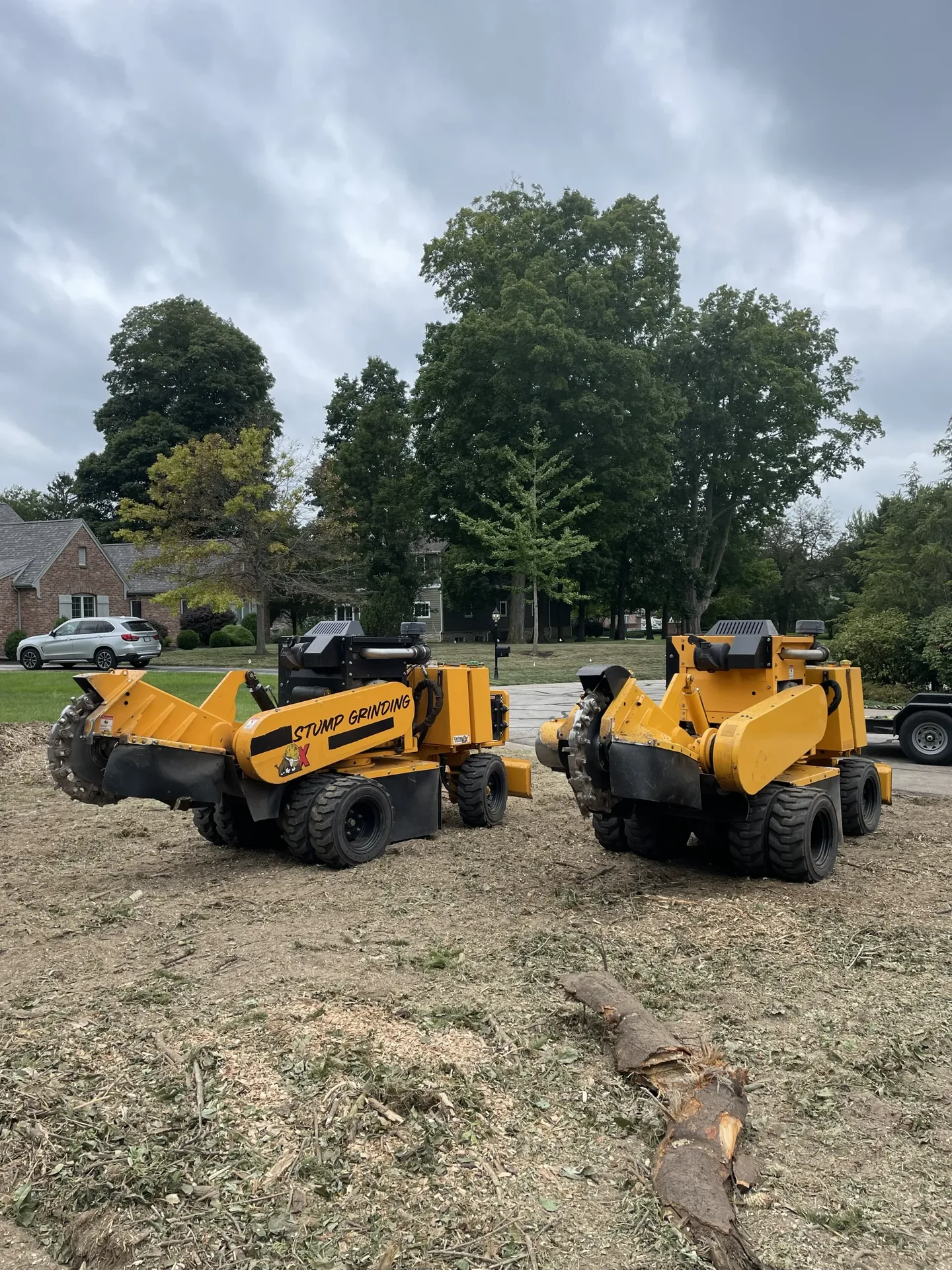 Better Way Land Management LLC two yellow stump grinder machines parked on cleared residential lot with wood debris visible