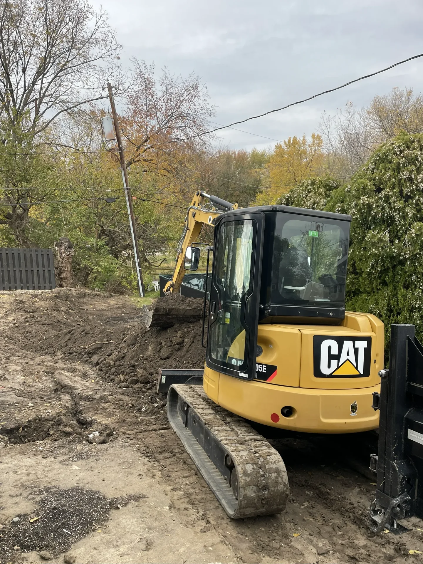 Better Way Land Management LLC CAT mini excavator performing residential backyard grading and earthwork on overcast autumn day