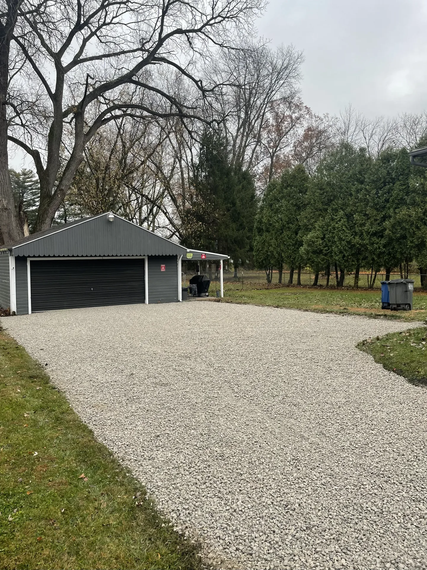Better Way Land Management LLC completed gravel driveway leading to gray detached garage with carport in residential backyard OH