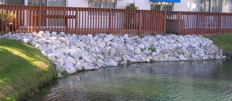 Better Way Land Management LLC riprap stone erosion control along residential pond shoreline with wooden fence in OH