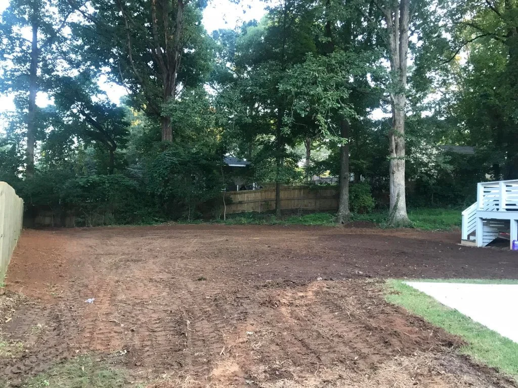 Better Way Land Management freshly graded residential backyard with red clay soil wooden fence and mature trees in Toledo OH
