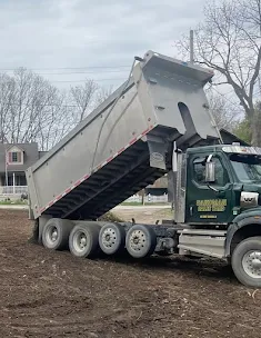 Better Way Land Management LLC dump truck with raised bed unloading material at residential work site during equipment operation