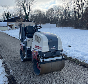 Better Way Land Management LLC Dynapac CC900 double drum roller compaction equipment parked on gravel driveway with winter snow background