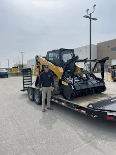 Better Way Land Management LLC team member standing beside Cat compact track loader with forestry mulcher attachment on flatbed trailer