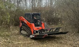 Better Way Land Management LLC compact track loader with brush cutter attachment clearing dense vegetation in wooded rural area